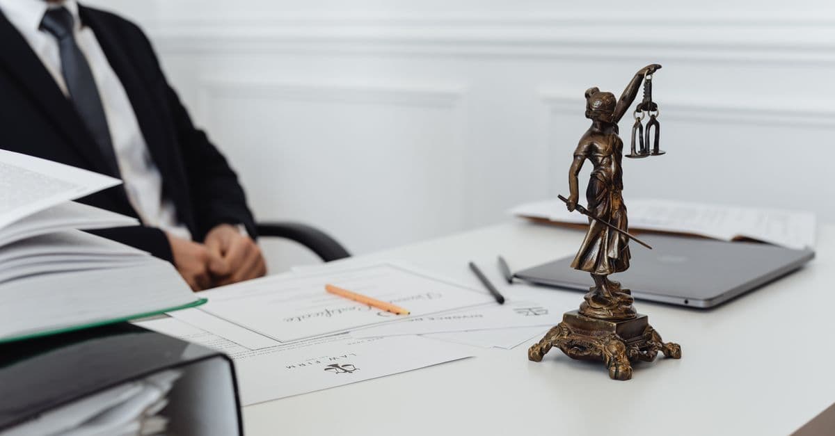 Bir hukuk bürosunda adalet terazisi heykelciği ve dava evrakları