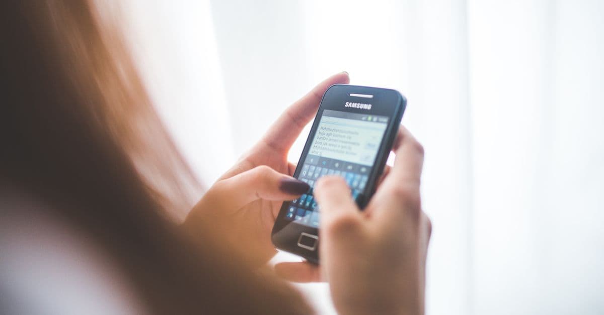 Elinde telefonla sosyal medya uygulamasında yazı yazan kişi